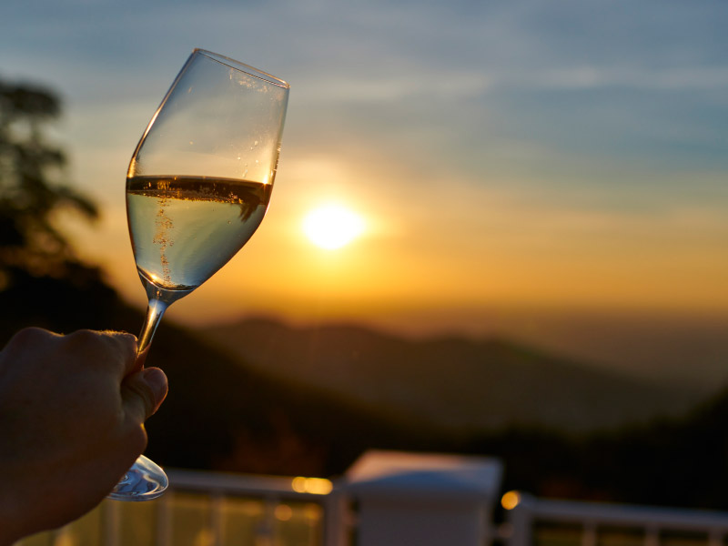Abendstimmung und Sonnenuntergang mit Hand, das Weinglas hält