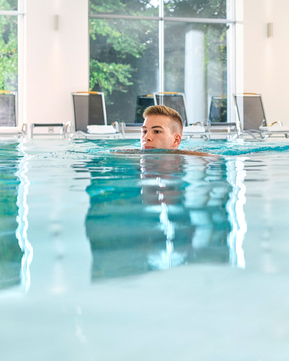 Bewegungsbad der Max Grundig klinkik, Schwimmbecken mit Schwimmer und Liegestühlen im Hintergrund