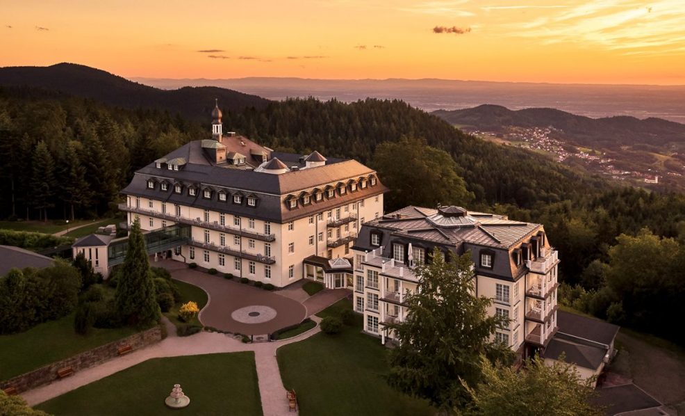 Blick auf die Max Grundig Klinik mit gepflegtem Garten und geschwungenen Wegen im warmen Abendlicht