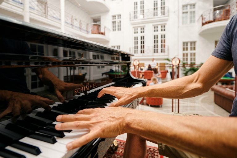 Person spielt Klavier in heller Innenlounge mit Sitzbereich im Hintergrund