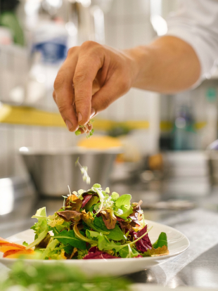 Hand garniert einen frischen Salat in einer professionellen Küche