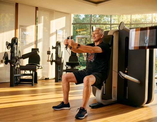 Mann trainiert an einem Fitnessgerät in einem Trainingsraum