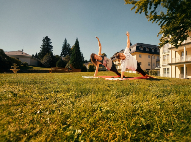 Zwei Frauen machen Übungen im Garten vor der Klinik
