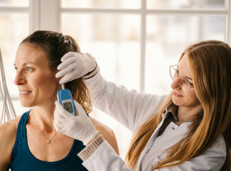 Fachangestellte untersucht das Ohr einer Patientin